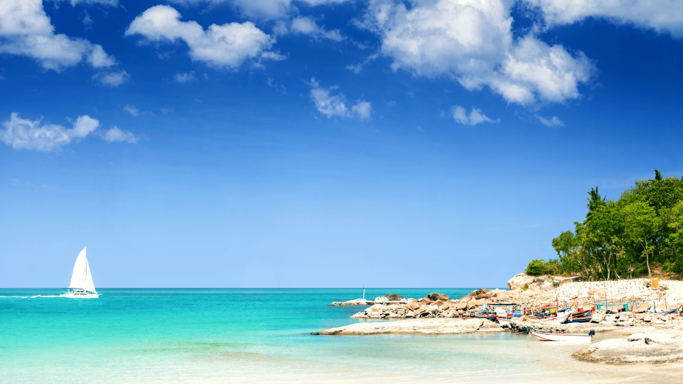 A picture of a sailboat heading towards an island.