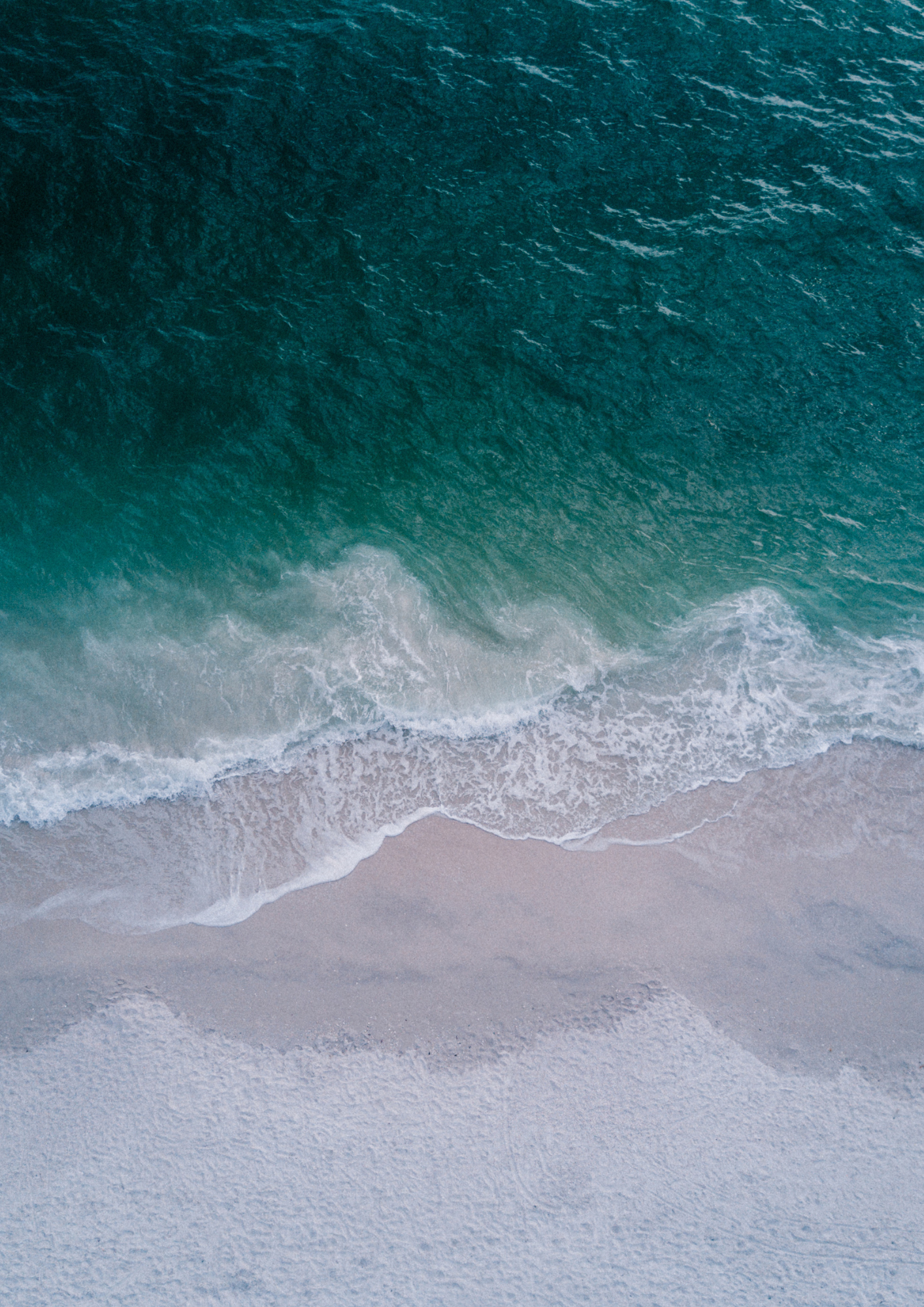 An overhead shot of waves rolling onto the ocean.