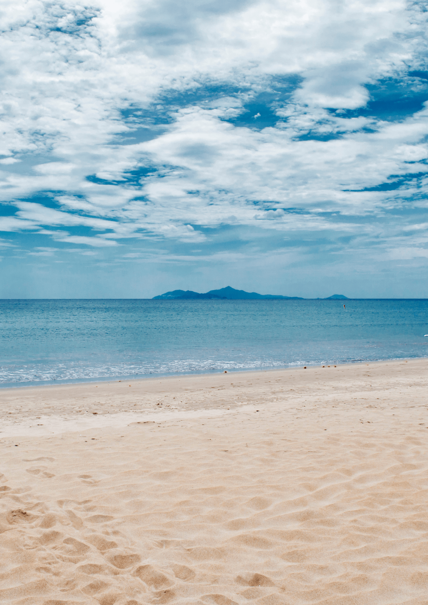 A distant picture of footprints on the beach.