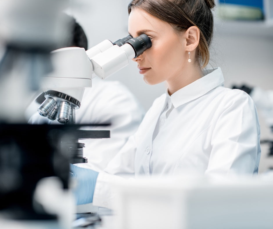 A women analyzing DNA under a microscope.